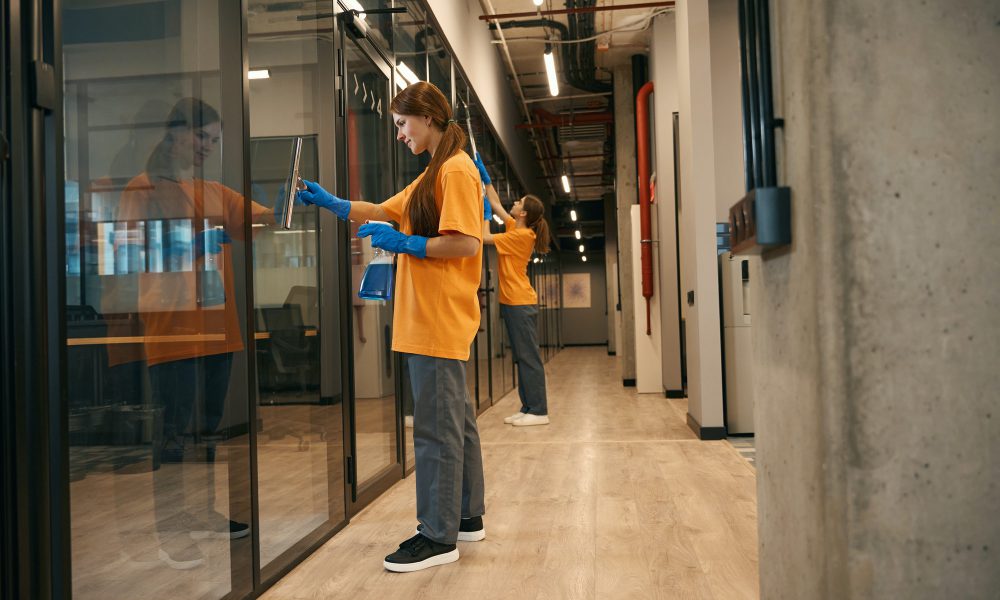 two-employees-cleaning-company-clean-the-mirrored-partitions-coworking-space.jpg